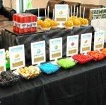 Eight snack items arranged in a colorful manner with signs depicting items found in in the Minecraft world. Food items include: chocolates, rock candy, fruit and vegetables.